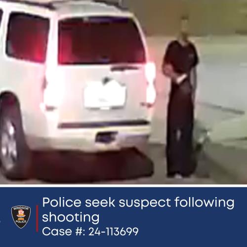 Surveillance photo of shooting suspect standing near vehicle.